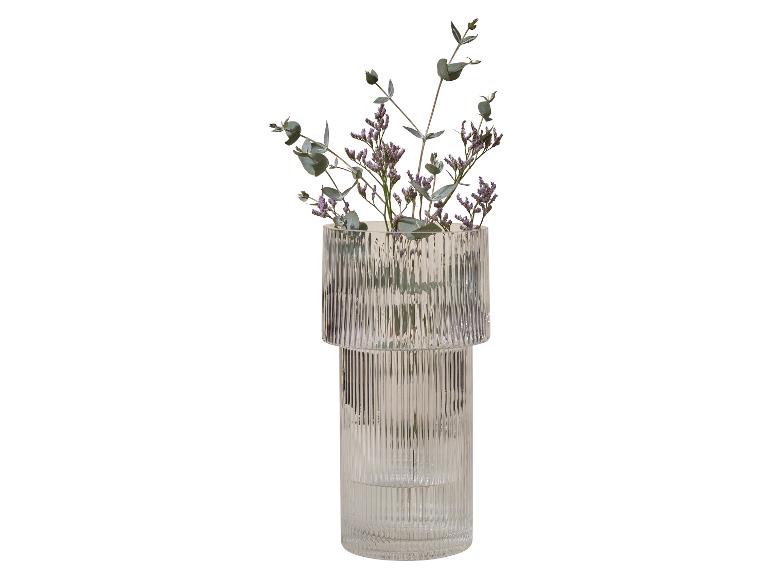 Glazen vaas met geribbelde textuur, gevuld met paarse bloemen en eucalyptus.