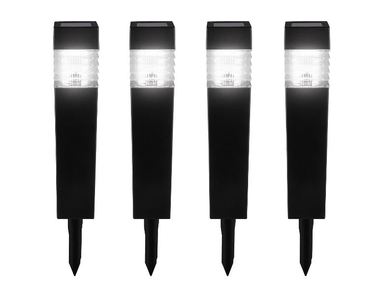 Vier zwarte solar tuinlampen met wit licht en grondpennen.