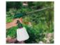 Hand houdt groene en witte tuinspuit vast, die water sproeit in een tuin.