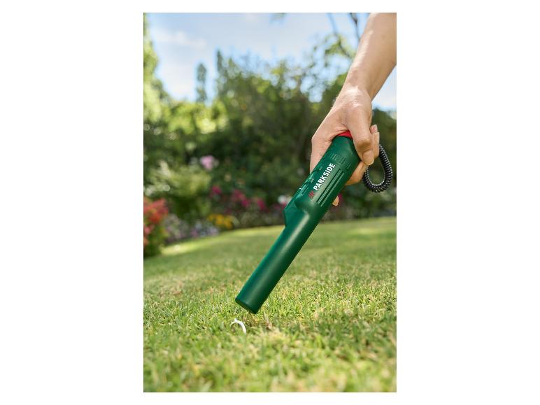 Handmetaaldetector zoekt naar een ring in het gras.