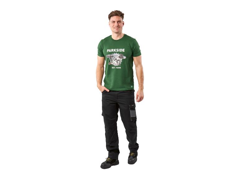 Man in groen T-shirt met gereedschapsopdruk en zwarte werkbroek.