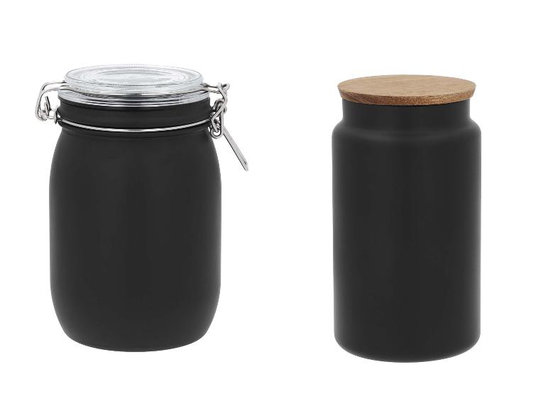 Twee zwarte voorraadpotten, één met een glazen deksel en metalen sluiting, de andere met een houten deksel.