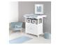 Babykamer met een witte commode, blauwe fauteuil en vloerkleed.