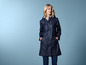 Een vrouw draagt een blauwe regenjas met capuchon.