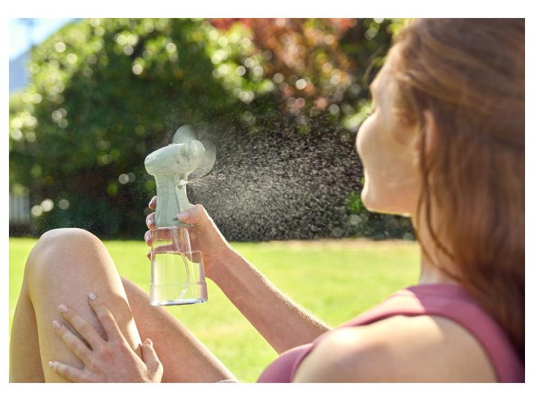 Draagbare ventilator en verstuiver verfrissen een vrouw buiten.