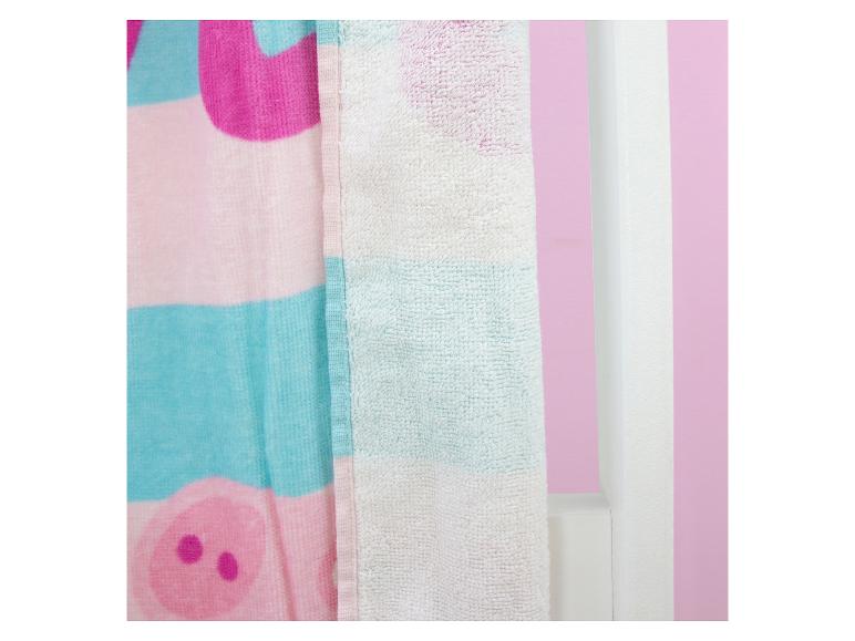 Roze en blauwe handdoek met varkenspatroon, hangend aan een witte muur.