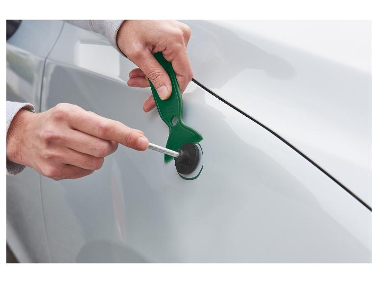 Handen gebruiken een deukreparatieset op een wit autospatscherm