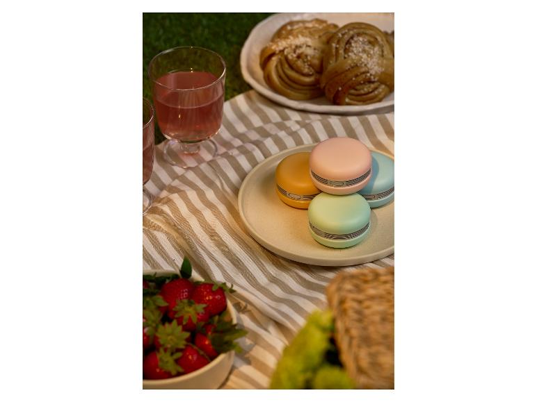 Picknick met kleurrijke macaronvormige draagbare ventilatoren, drankjes, gebak en aardbeien.
