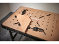 Werkbank met geperforeerd blad en klemmen die een houten plank vasthouden.