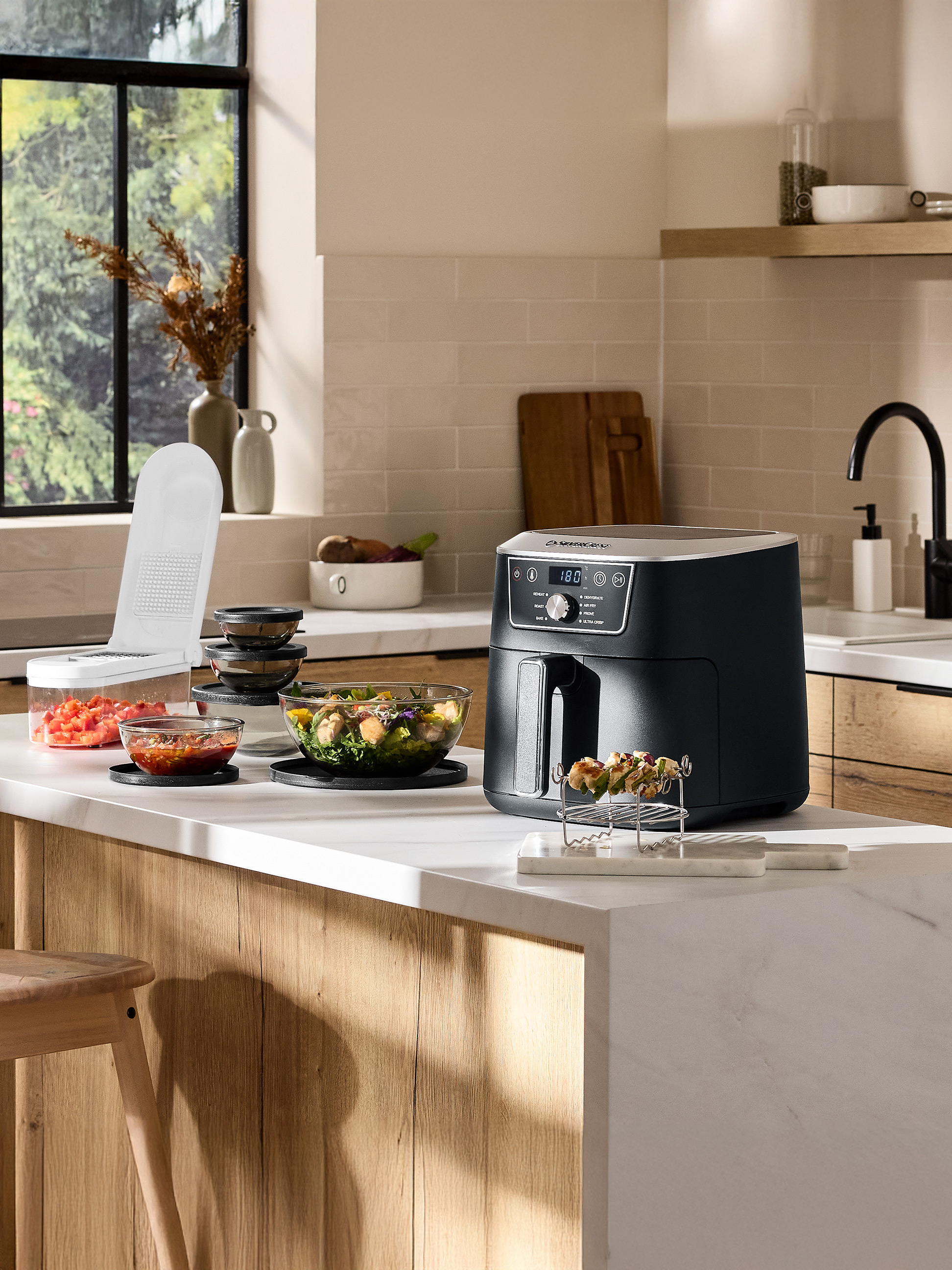 Keukenblad met een airfryer, hakmolen en kommen met salade en salsa.