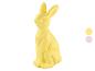 Gele paashaasfiguur met twee kleurstaaltjes rechts.