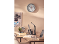 Wandklok met thermometer en hygrometer, prikbord en bureaulamp op een bureau.
