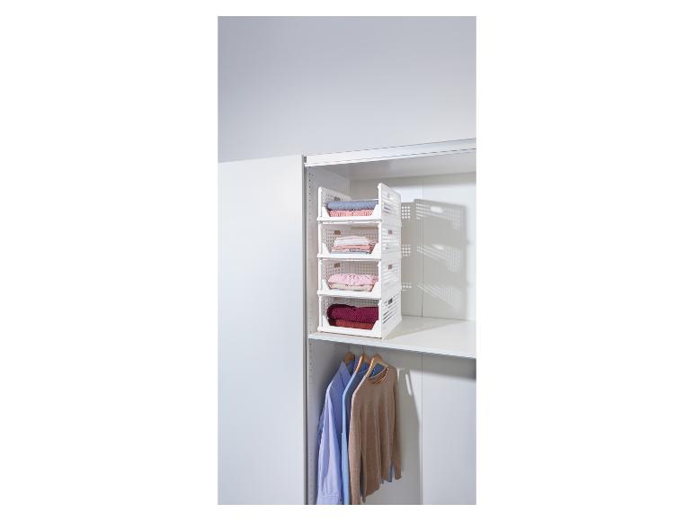 Witte vierlaagse opbergrek gevuld met opgevouwen kleding in een kast.