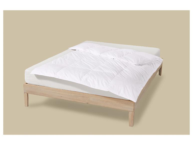 Houten bed met wit matras, dekbed en kussen.