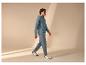 Man in een teal hoodie en bijpassende joggingbroek, lopend met witte en marineblauwe sneakers.