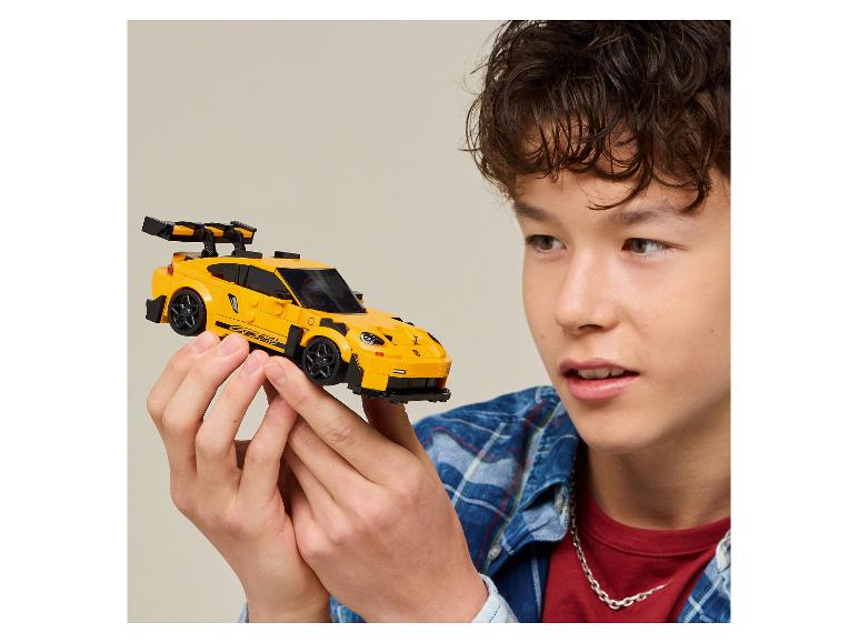 Een jongen houdt een gele speelgoedraceauto vast en kijkt er aandachtig naar.