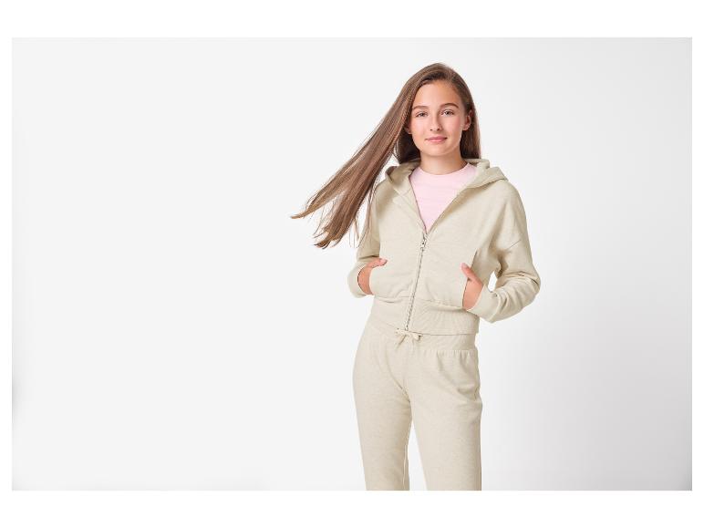 Tienermeisje in beige hoodie met rits en bijpassende joggingbroek.