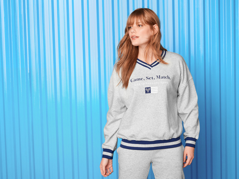 Een grijze sweater met een tennis-thema en bijpassende broek.