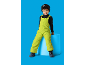Jongen met zwarte muts en groene winteroverall zit op een blauwe cilinder.