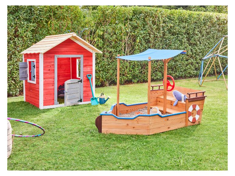 Buitenspeeltuin voor kinderen met een rood speelhuisje en een zandbak in de vorm van een boot