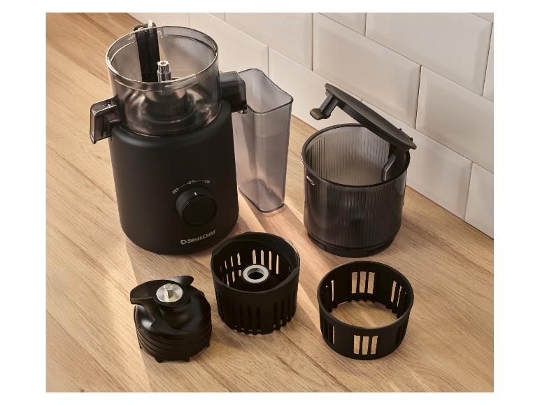 Zwarte keukenmachine met gedemonteerde accessoires op een houten tafel.