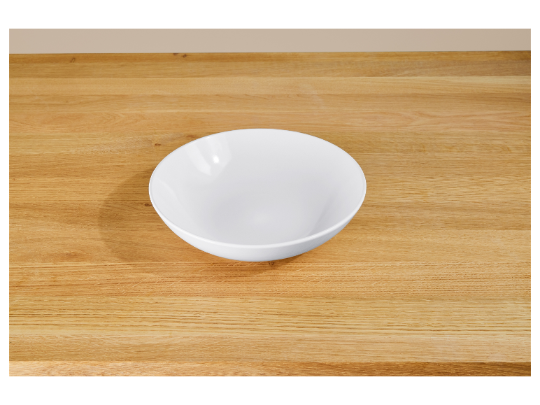 Een witte kom op een houten tafel.