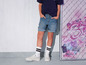 Een persoon draagt ​​jeans shorts en witte sneakers.