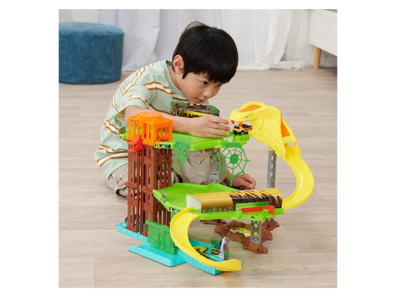 Een jongen speelt met een jungle-thema speelset met een autobaan en een cobra.