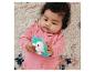 Baby in roze romper houdt blauw-wit egel bijtspeeltje vast.