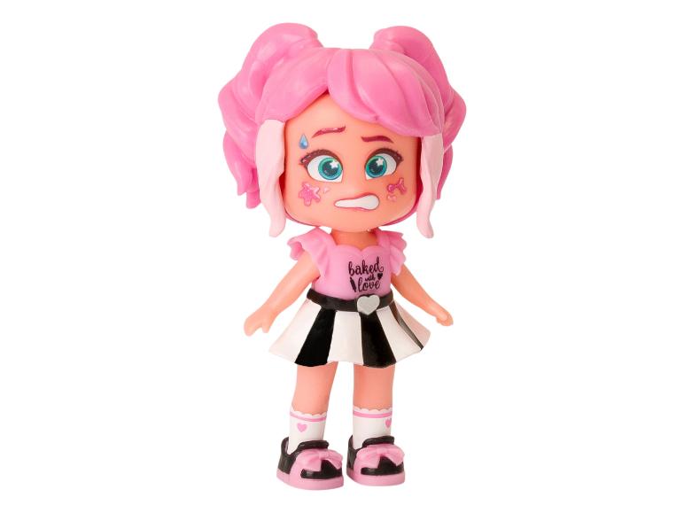 Een roze pop met een zwart-wit gestreepte rok en een 'Baked with Love' shirt.