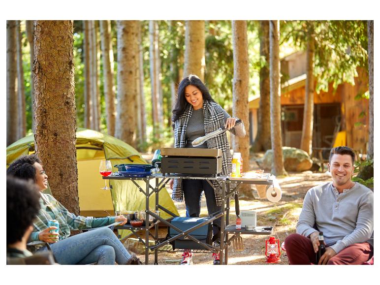 Een vrouw kookt op een Coleman-fornuis in de wildernis.