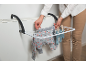 Vrouw hangt babykleding op een droogrek bevestigd aan een radiator.