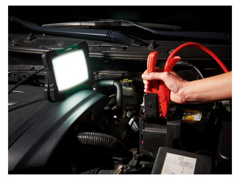 LED-werklamp en startkabels aangesloten op een autoaccu.