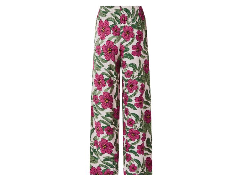 Damesbroek met wijde pijpen en tropisch patroon van roze bloemen en groene bladeren.