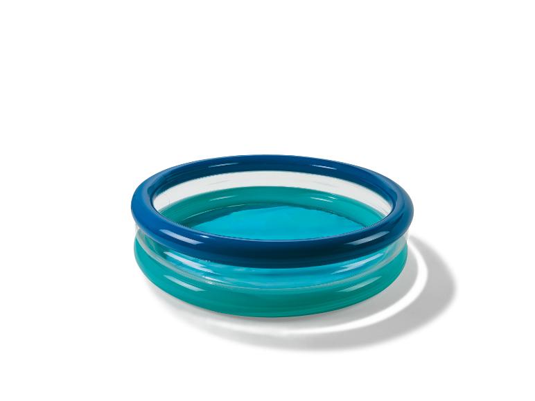 Opblaasbaar zwembad met twee blauwe ringen, gevuld met water, werpt een schaduw.