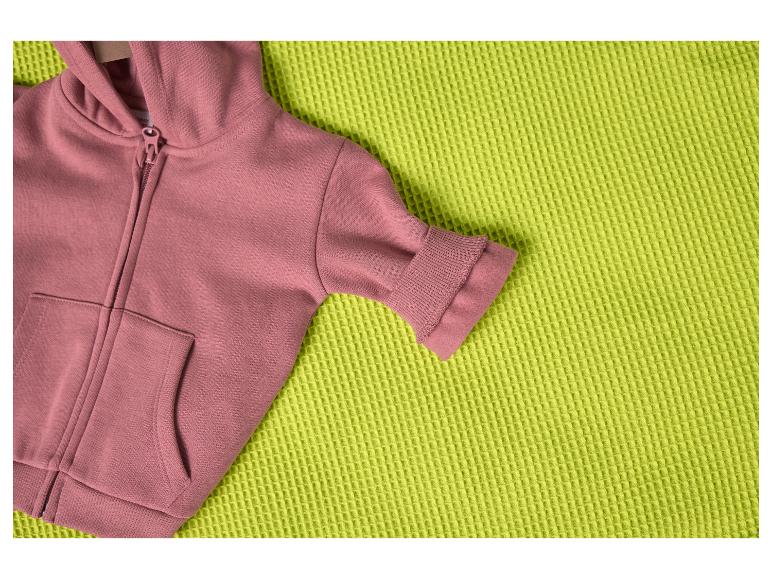 Roze hoodie op een getextureerde limoengroene deken.