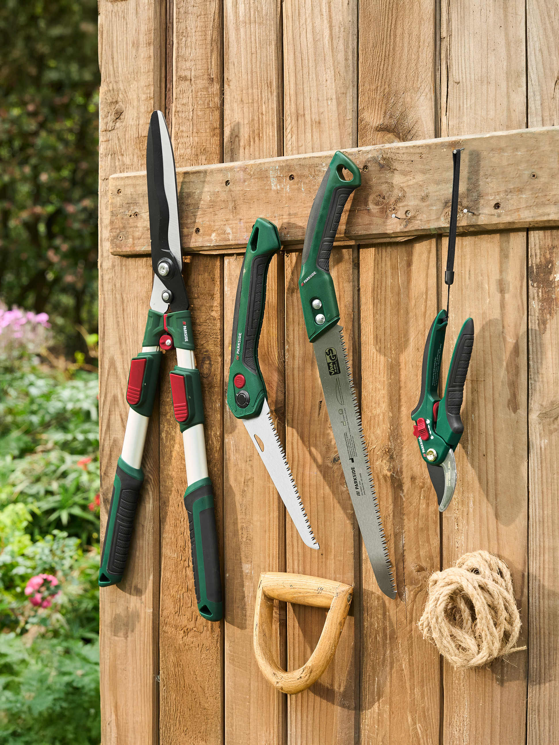 PARKSIDE tuinscharen, zagen en snoeischaren hangend aan een houten schutting.