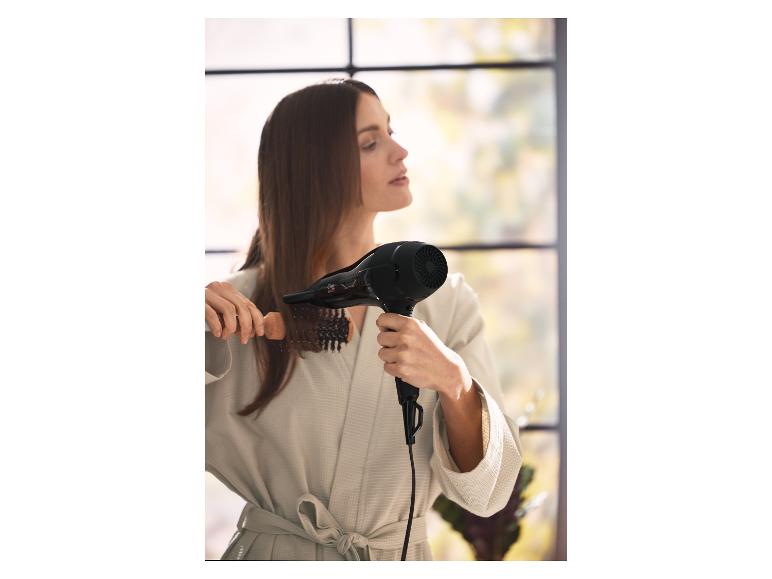 Vrouw droogt haar met een föhn en een ronde borstel.