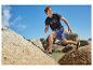 Man rent in zwart T-shirt en blauwe korte broek over rotsen.