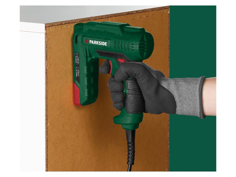 Een hand houdt een elektrische nietmachine tegen een houten plank.