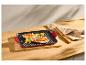 Rode grillpan met gegrilde kip en groenten op een houten plank.