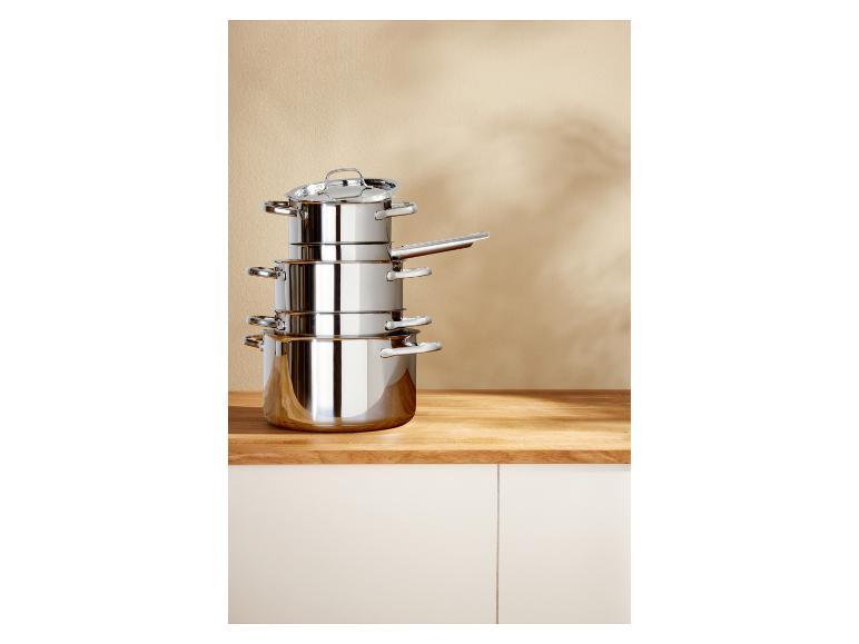 Set roestvrijstalen potten en pannen gestapeld op een houten aanrecht.