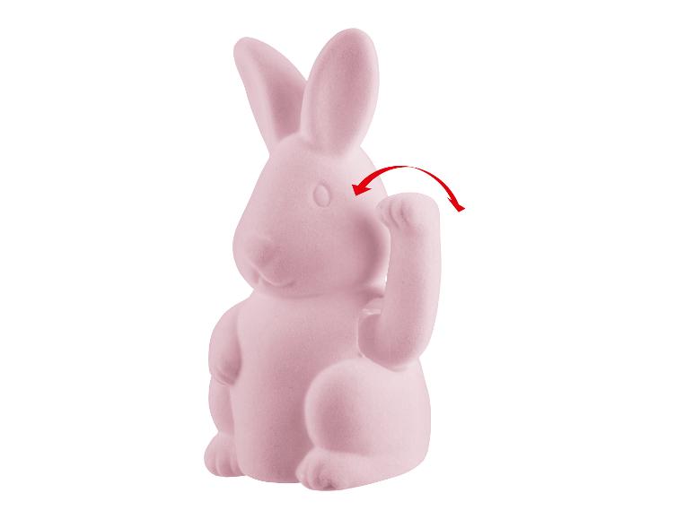 Een roze konijnenbeeldje met een opstaand pootje.