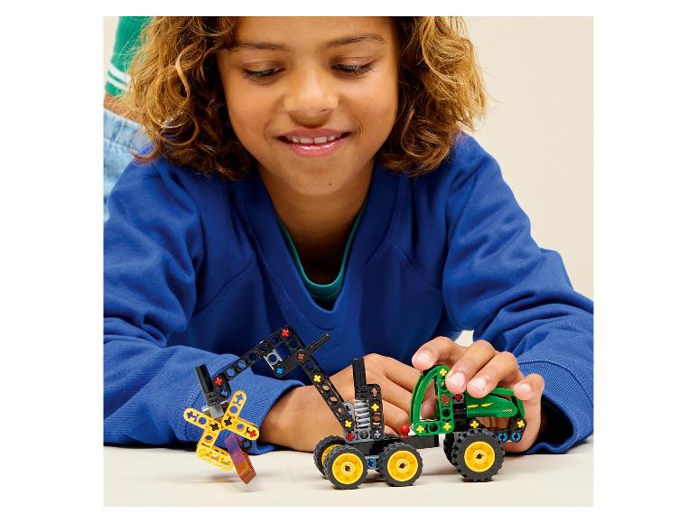 Een kind speelt met een speelgoedtractor en een graafmachine gemaakt van bouwblokken.