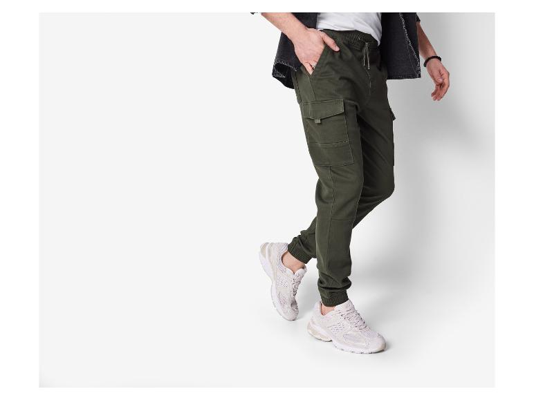 Man in groene cargobroek en witte sneakers.