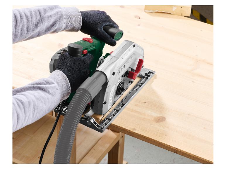 Handen zagen een houten plank met een cirkelzaag met stofafzuigslang.