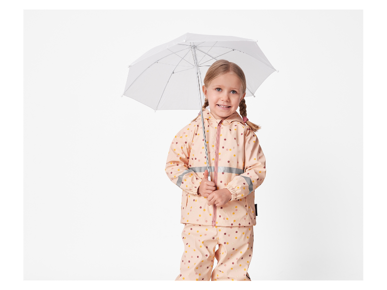 Meisje in polkadot regenpak met een witte paraplu.