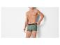 Man in groene boxershort met patroon die de tailleband aanpast.