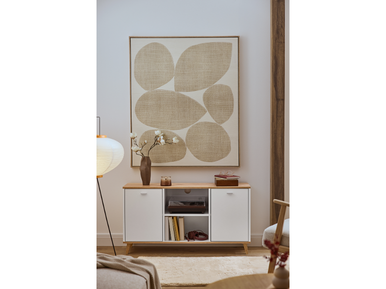 Een witte ladekast met houten blad, versierd met een abstract schilderij en een vaas met bloemen.