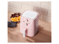 Een roze Silvercrest airfryer staat op een houten tafel naast friet en kippenvleugels.